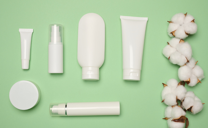 White plastic tubes, jars, and containers for cosmetic products on a green background, advertising and branding of products White plastic tubes, jars, and containers for cosmetic products on a green background, advertising and branding of products