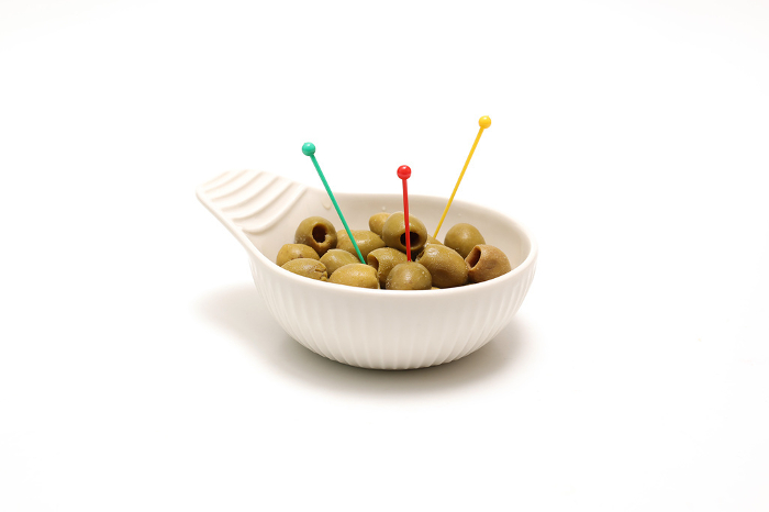 Olive oil pickles in a white ceramic bowl with white background