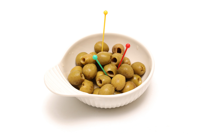 Olive oil pickles in a white ceramic bowl with white background