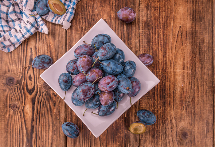 Portion of Plums on wooden background, selective focus Portion of Plums on wooden background, selective focus, by Zoonar Christoph Sch