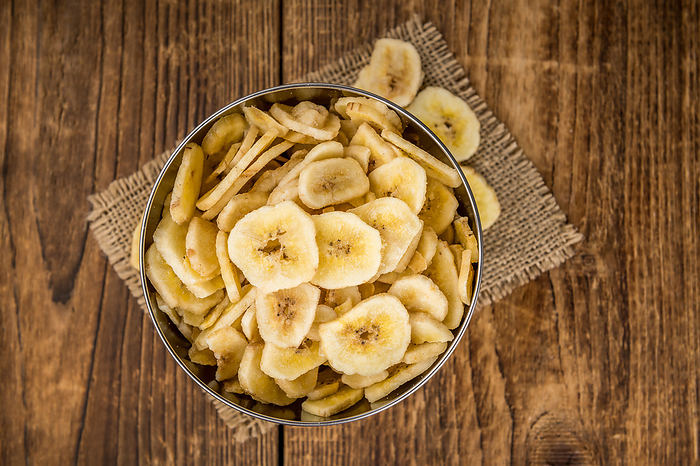 Portion of Dried Banana Chips on wooden background, selective focus Portion of Dried Banana Chips on wooden background, selective focus, by Zoonar Christoph Sch