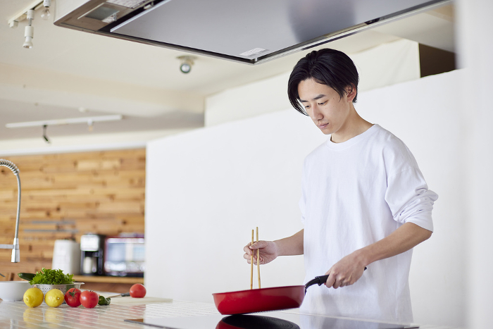 Young Japanese man cooking in the kitchen (People)