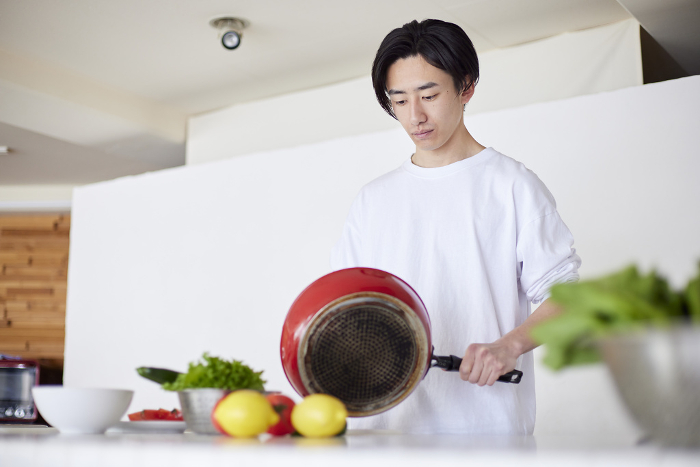 Young Japanese man cooking in the kitchen (People)