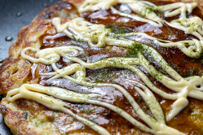 Close-up of okonomiyaki (with sauce, mayonnaise, and aonori seaweed).