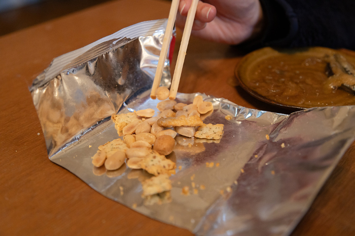 Hand eating snacks with chopsticks