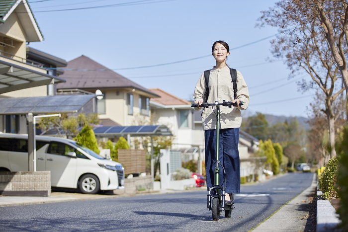 Japanese woman riding an electric kickboard in a residential area (People)