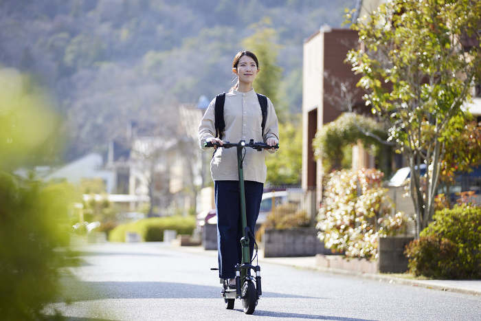 Japanese woman riding an electric kickboard in a residential area (People)