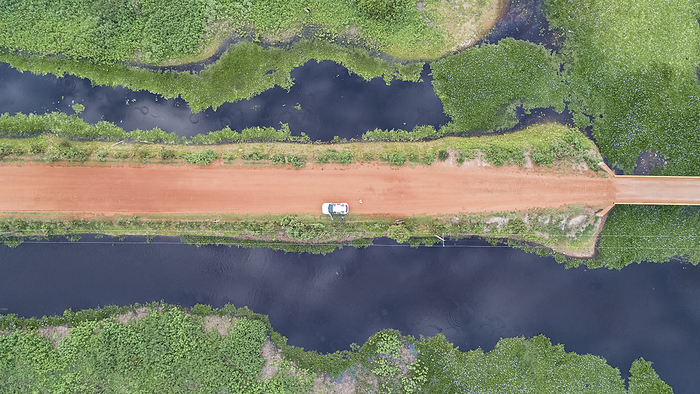 Aerial view vertical down of Transpantaneira dirt road with a car and adjoining blue lagoons and gre Aerial view vertical down of Transpantaneira dirt road with a car and adjoining blue lagoons and gre, by Zoonar Uwe Bergwitz