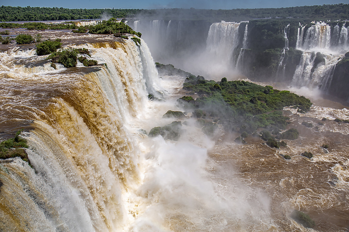 View of powerful Iguazu Falls near Devil s Throat with brown and white water in lush green vegetatio View of powerful Iguazu Falls near Devil s Throat with brown and white water in lush green vegetatio, by Zoonar Uwe Bergwitz
