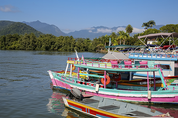 View to colorful tour boats in the water waiting for tourists at a pier, with green mountains in the background, Paraty, Brazil, Unesco World Heritage View to colorful tour boats in the water waiting for tourists at a pier, with green mountains in the background, Paraty, Brazil, Unesco World Heritage, by Zoonar Uwe Bergwitz