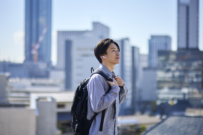 Japanese university student wearing wireless earphones on his way to school (People)