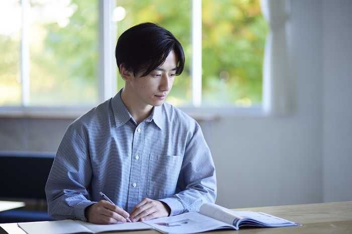 A Japanese university student studying in the living room of his house.