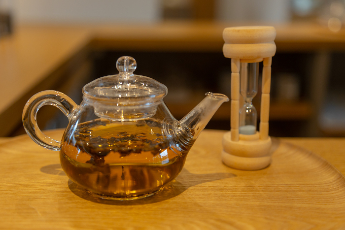 Brewing tea in a glass teapot with an hourglass beside it to measure the time.