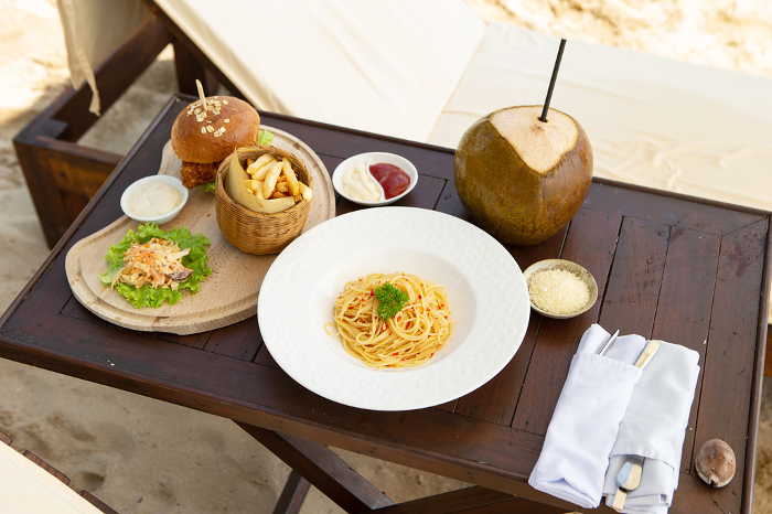 Pasta and chicken burgers on a beach table at the resort