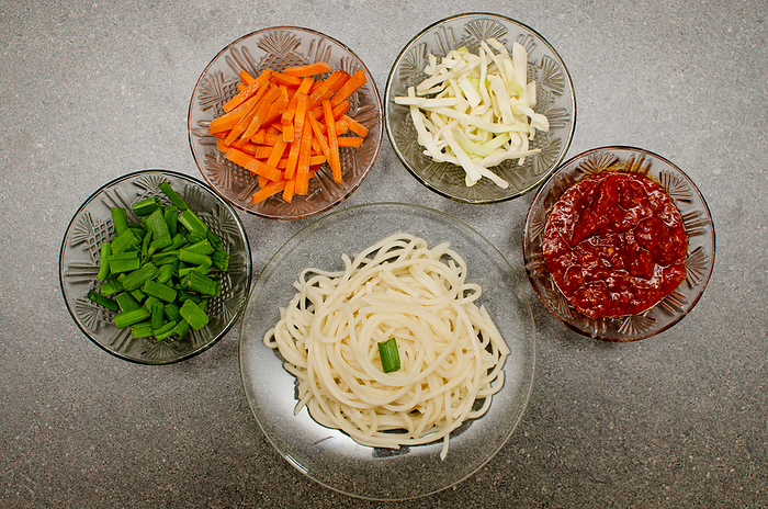 Preparation of Veg Schezwan Hakka Noodles which includes boiled noodles, fresh vegetables and schezwan sauce on Gray background Preparation of Veg Schezwan Hakka Noodles which includes boiled noodles, fresh vegetables and schezwan sauce on Gray background, by Zoonar RealityImages