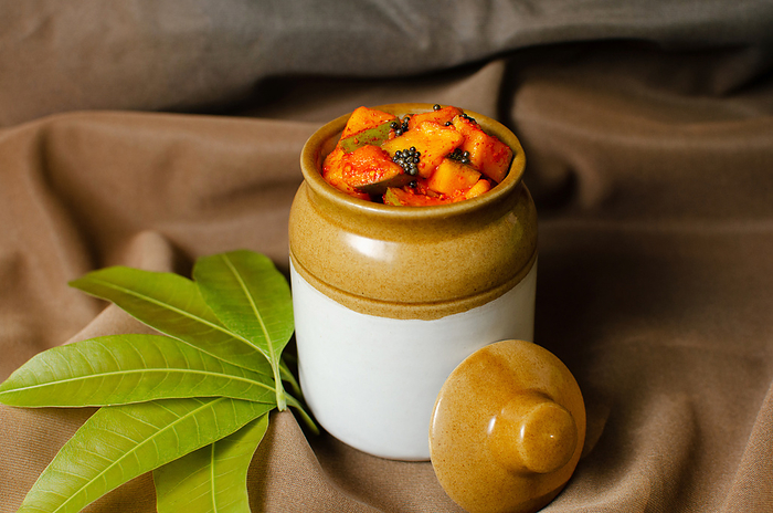 Homemade raw mango pickle in a traditional ceramic jar on Brown background Homemade raw mango pickle in a traditional ceramic jar on Brown background, by Zoonar RealityImages