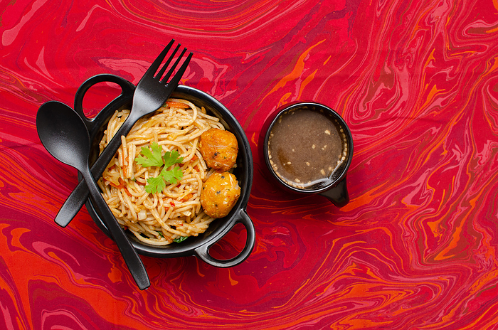 Veg Schezwan Hakka Noodles served in a Black colored bowl with Manchow soup on Gray background Veg Schezwan Hakka Noodles served in a Black colored bowl with Manchow soup on Gray background, by Zoonar RealityImages