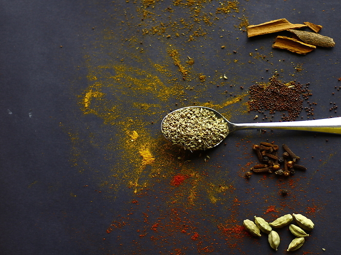Indian spices, Cumin seeds on spoon, mustard seeds, cinnamon,  cardamon and cloves on dark background Indian spices, Cumin seeds on spoon, mustard seeds, cinnamon,  cardamon and cloves on dark background, by Zoonar RealityImages