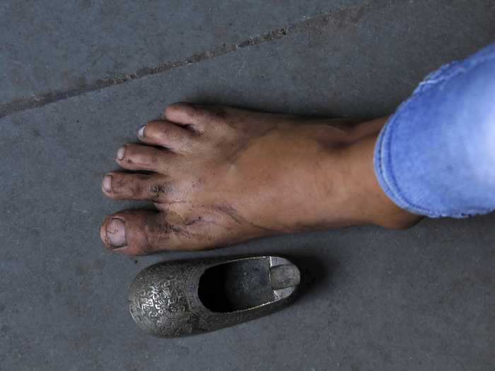 Contrast of bare foot of woman with small shoe of child, by Zoonar/RealityImages