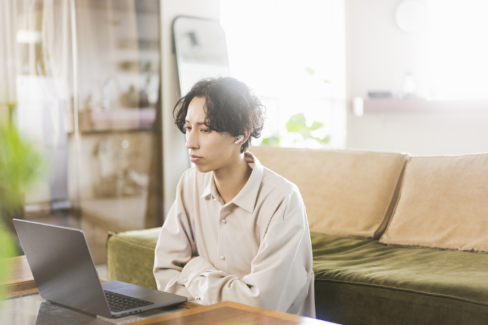 Young Japanese man working remotely from home using a laptop computer (People)