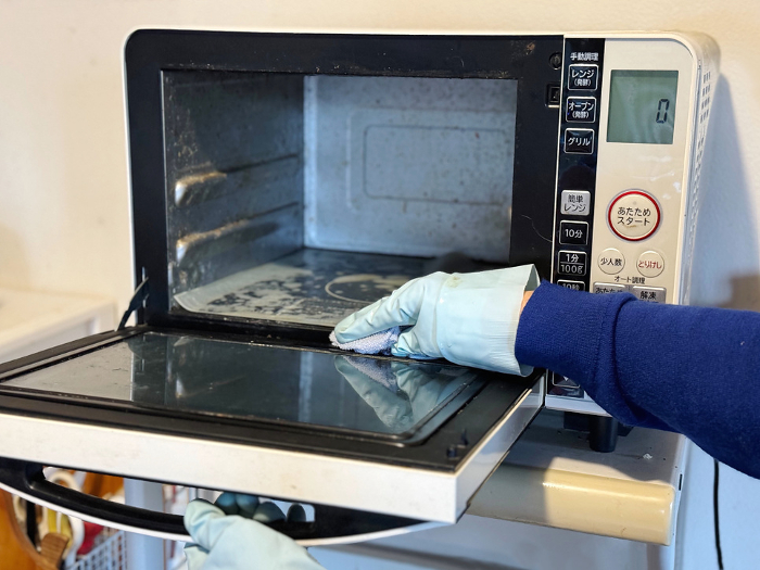 Woman's hand cleaning inside microwave oven