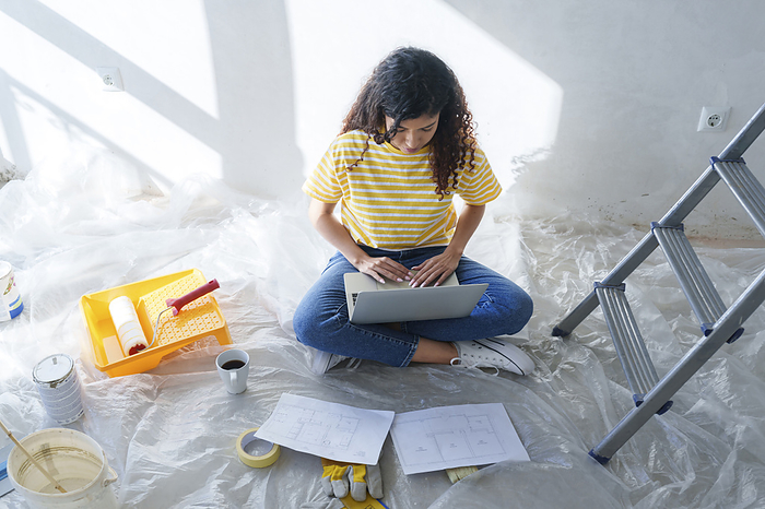 Young woman using laptop in room under renovation