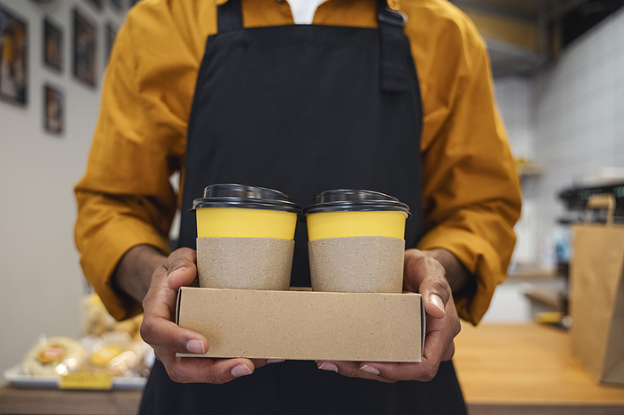 Barista holding takeaway coffee cups at cafe