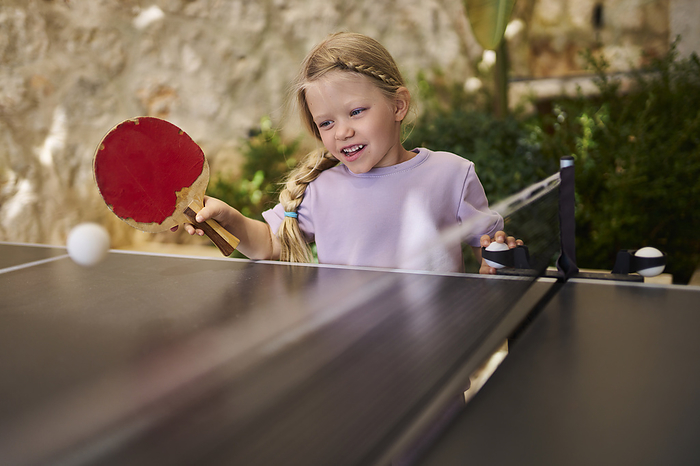Girl having fun playing table tennis at villa