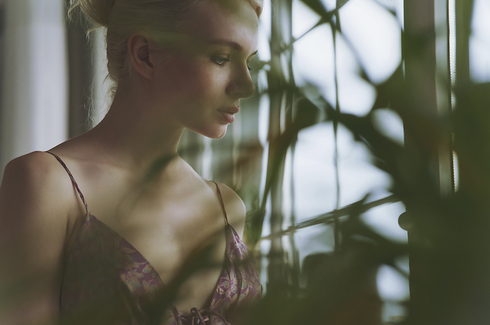 Young pensive blond woman looking at window Young pensive woman looking out of window