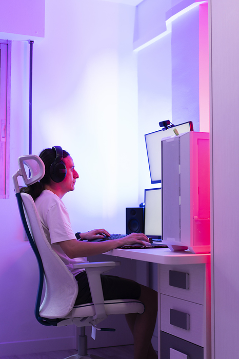 Professional gamer wearing headphones and playing game on computer