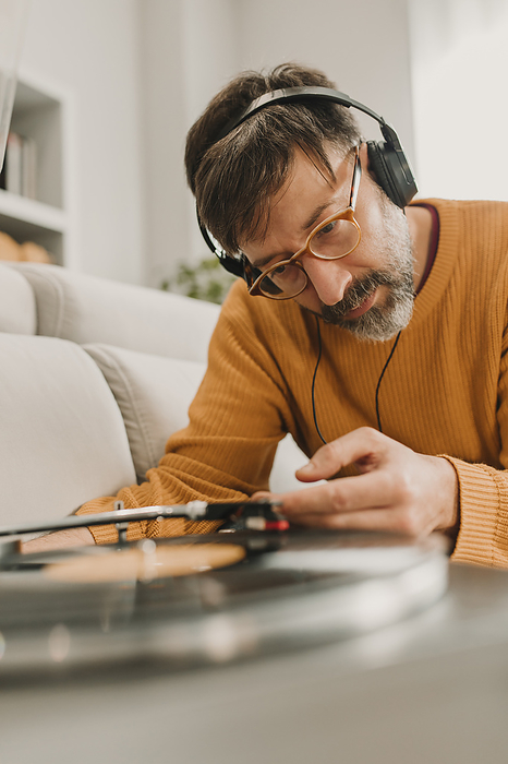 Man listening to music and adjusting needle on vinyl