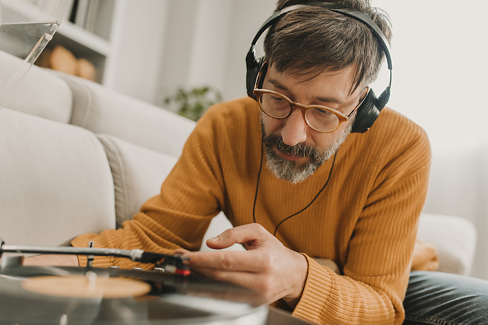 Man listening to music and adjusting needle on old-fashioned record