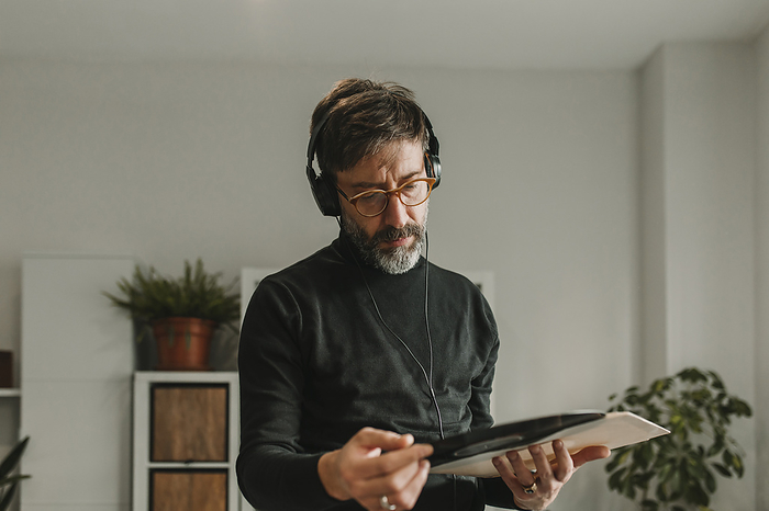 Man listening to music and examining vinyl at home