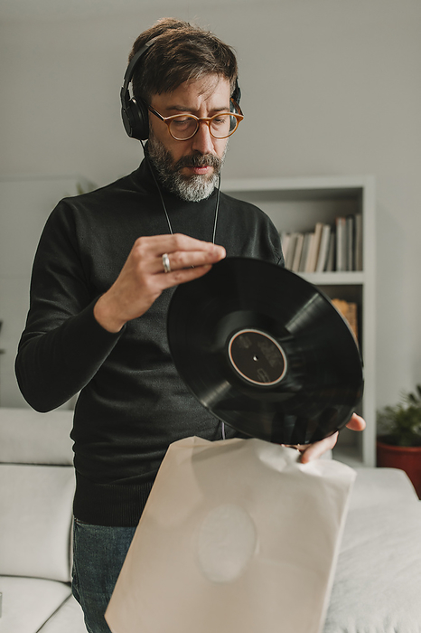 Man listening to music and holding vinyl at home