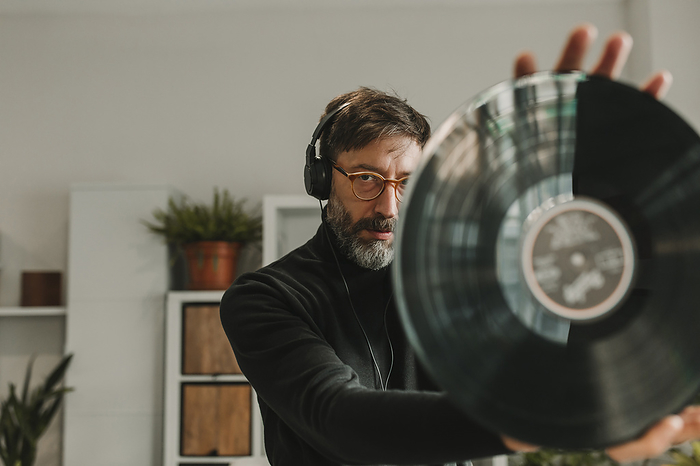Man listening to music and analyzing vinyl at home