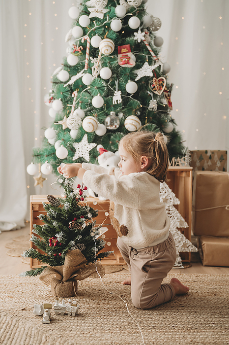 Girl decorating small Christmas tree at home