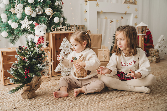 Girls playing and decorating small Christmas tree at home