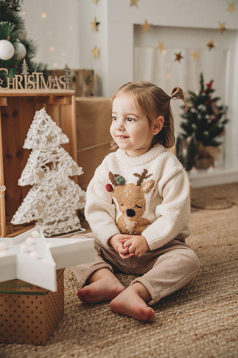 Smiling girl sitting near Christmas decoration at home