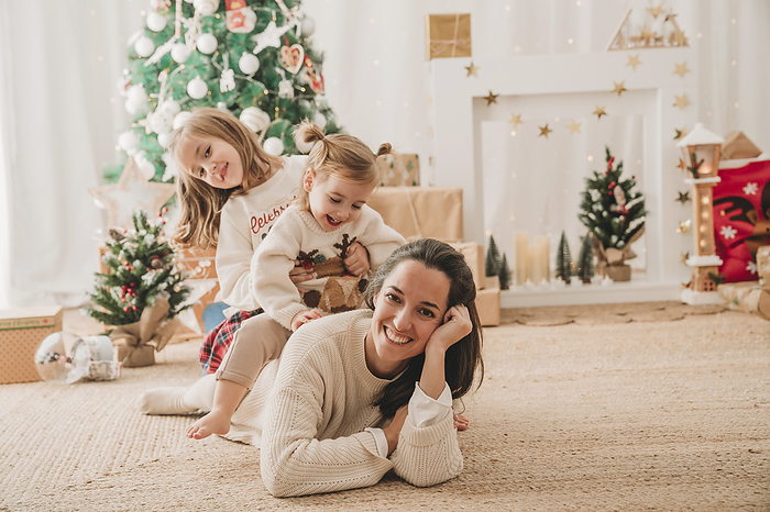 Mother with daughters enjoying near Christmas decoration at home