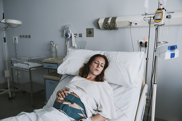 Pregnant woman in pain lying on hospital bed