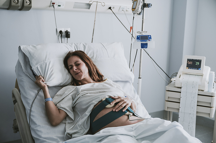 Pregnant woman in pain on bed at hospital