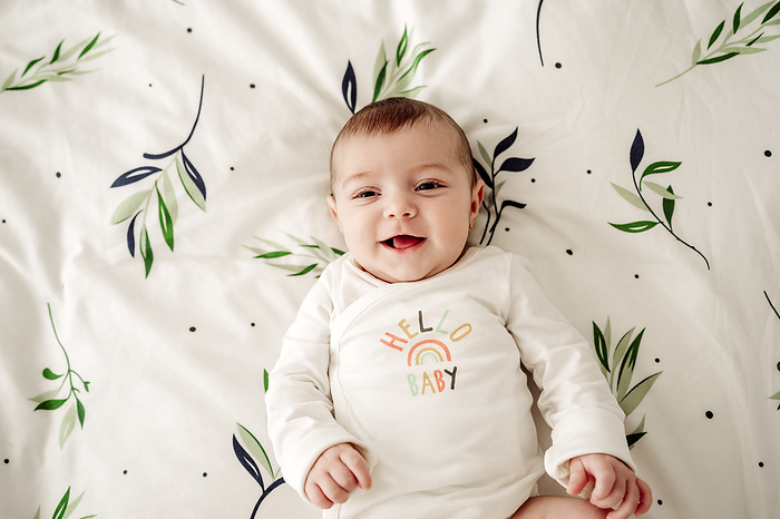 Smiling baby girl lying in bed at home