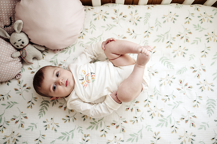 Cute baby girl lying in crib at home