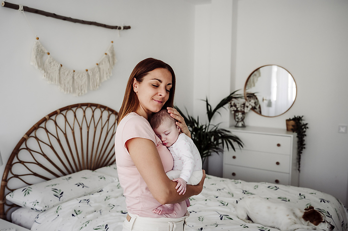 Smiling mother taking care of daughter in bedroom at home