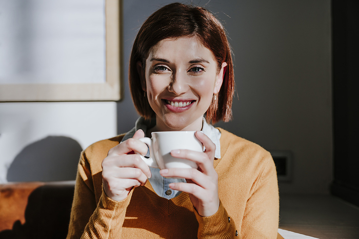 Smiling woman holding coffee cup in cafe