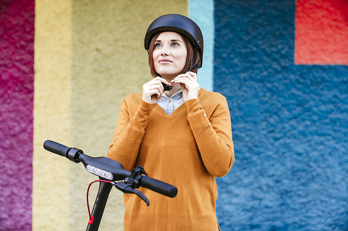 Smiling woman wearing helmet in front of multi colored wall