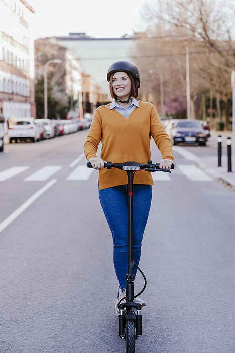 Happy woman standing with electric push scooter on road
