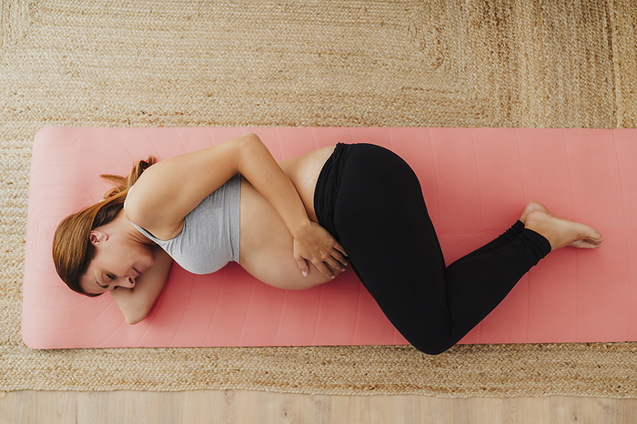 Pregnant woman lying on exercise mat at home