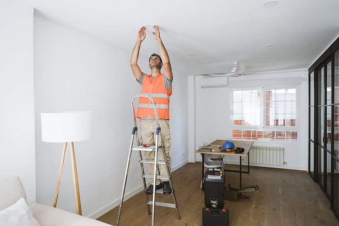 Repairman standing on ladder and working at home