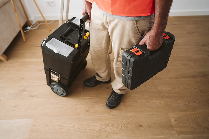 Repairman standing with tool boxes at house under renovation